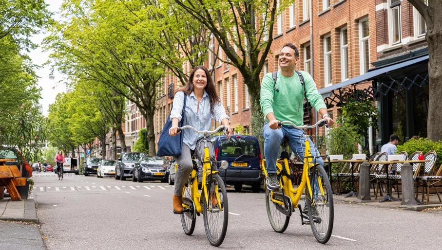 A couple on rental bikes from Yellow Bike cycle through Bosboom Toussaintstraat.