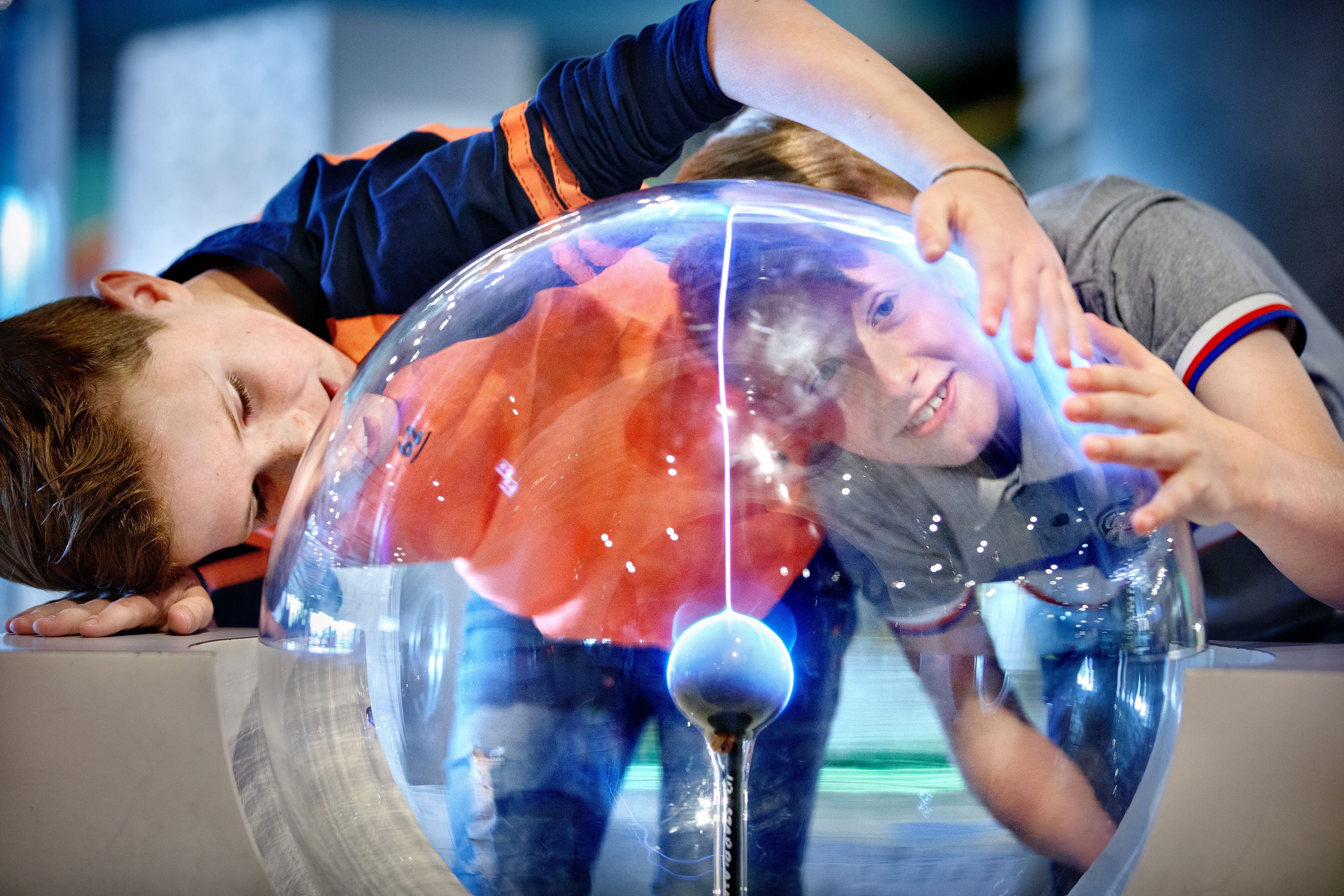 Twee jongens leggen hun hand op de teslabol in NEMO