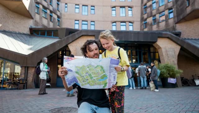 Father and daughter checking the 24 uur Zuidoost program in front of het Zandkasteel