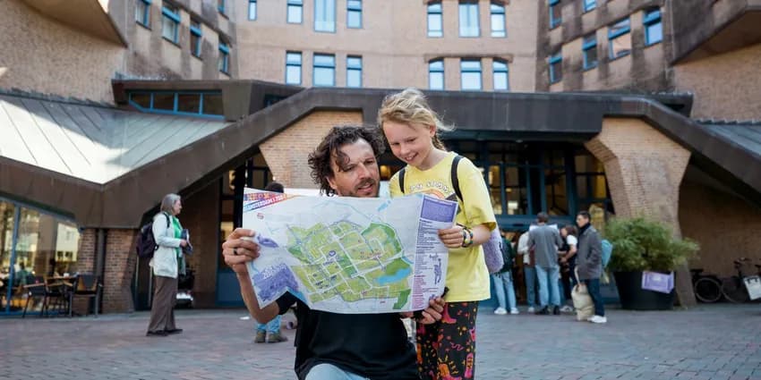 Father and daughter checking the 24 uur Zuidoost program in front of het Zandkasteel