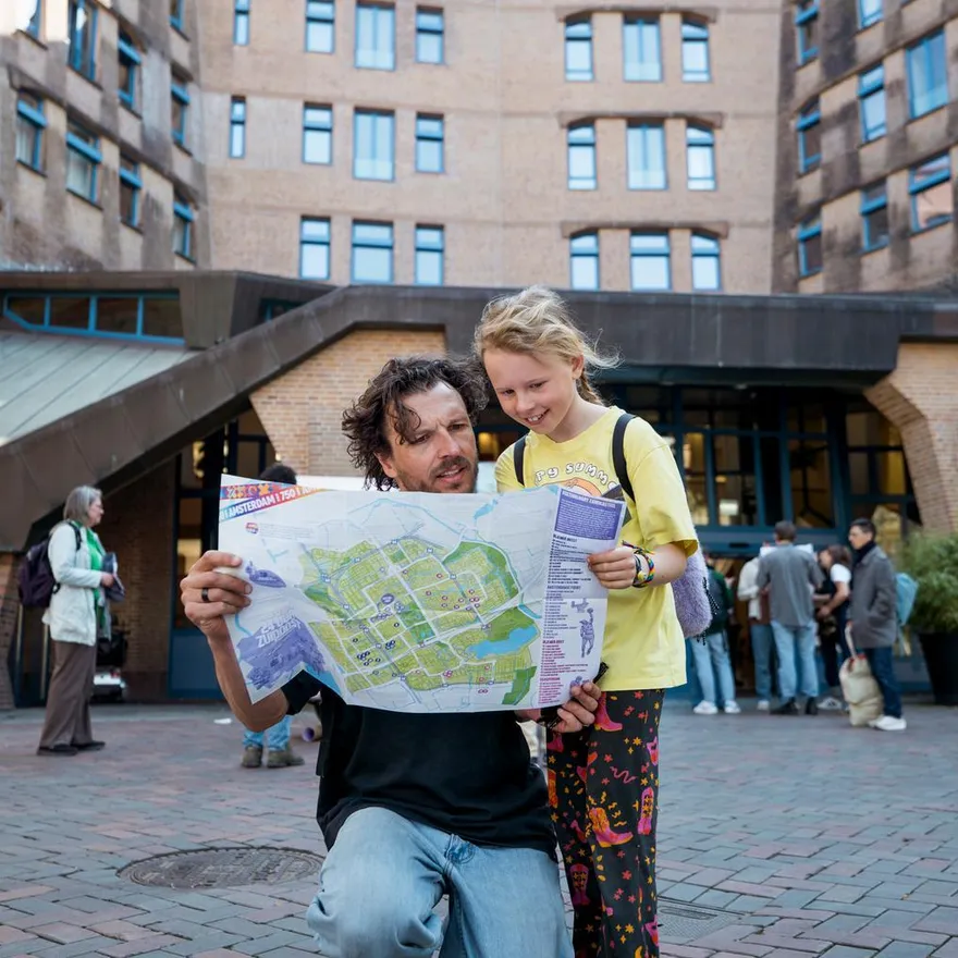 Father and daughter checking the 24 uur Zuidoost program in front of het Zandkasteel