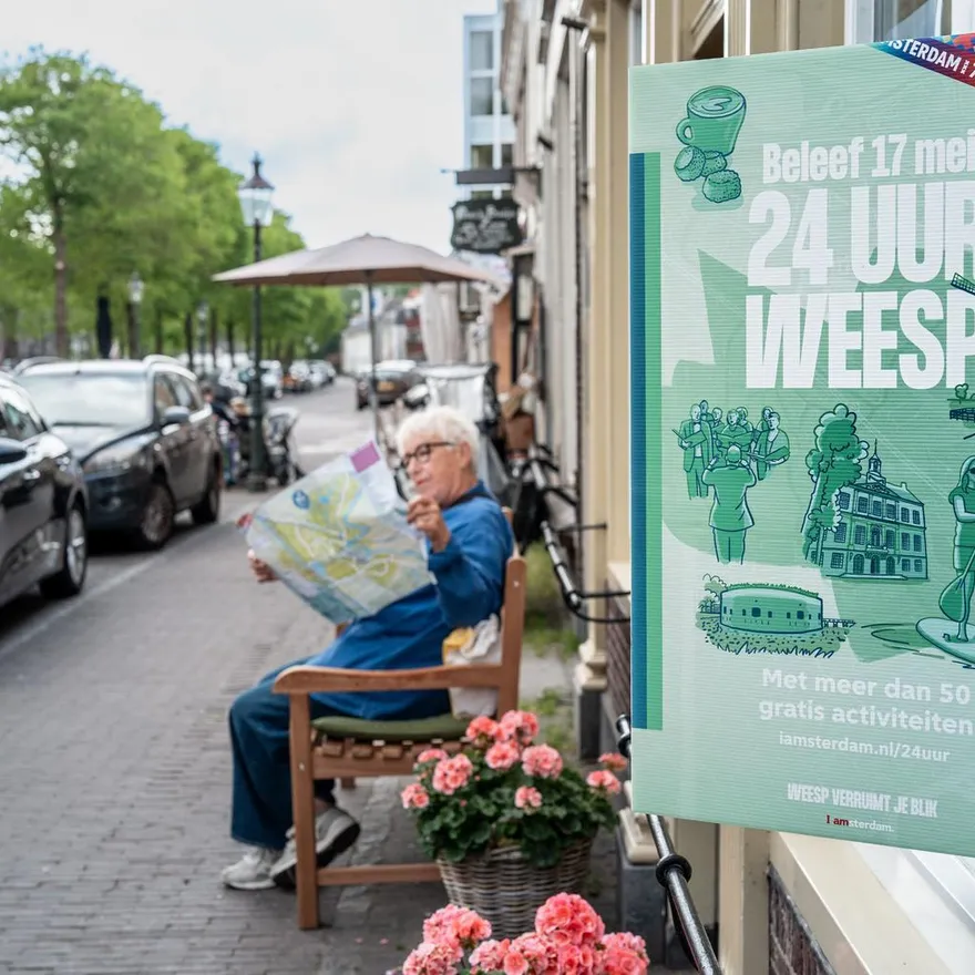 24 uur Weesp Branding, woman on a bench checks the flyer.