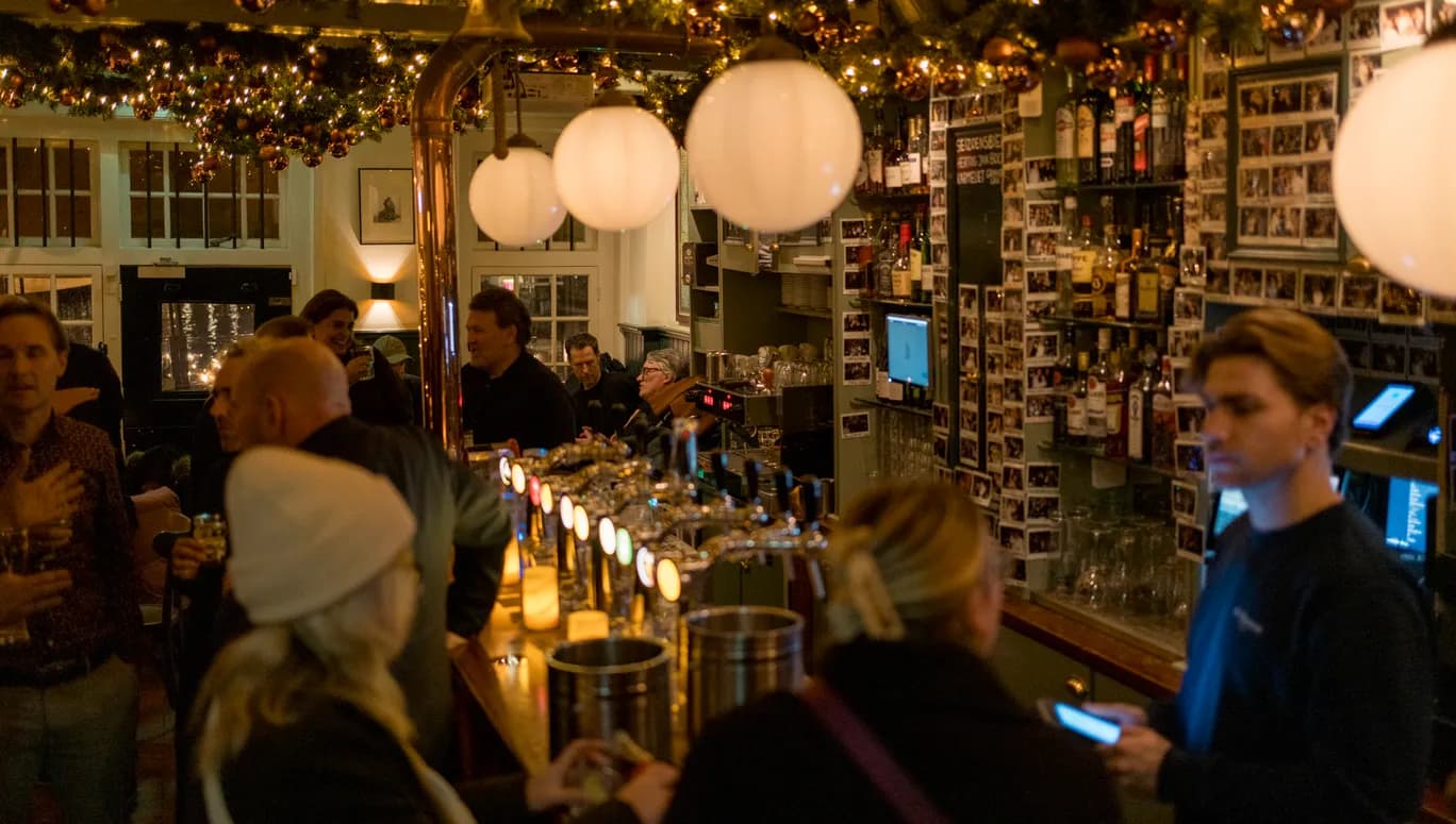 People sitting inside brown bar café De Sluyswacht.