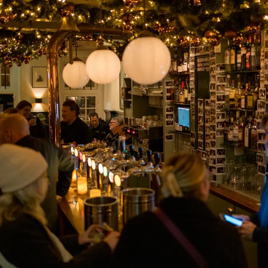 People sitting inside brown bar café De Sluyswacht.