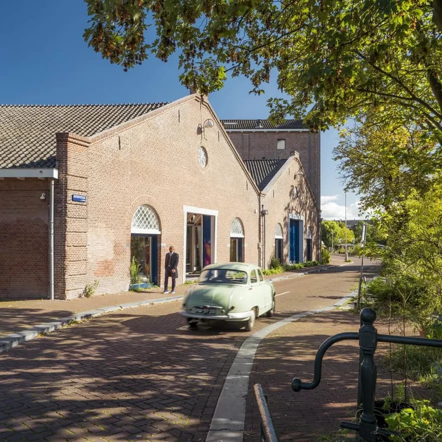A oldtimer car driving over a sunny Entrepotdok during early autumn.