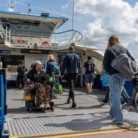 A person in an electric wheelchair exits the ferry.