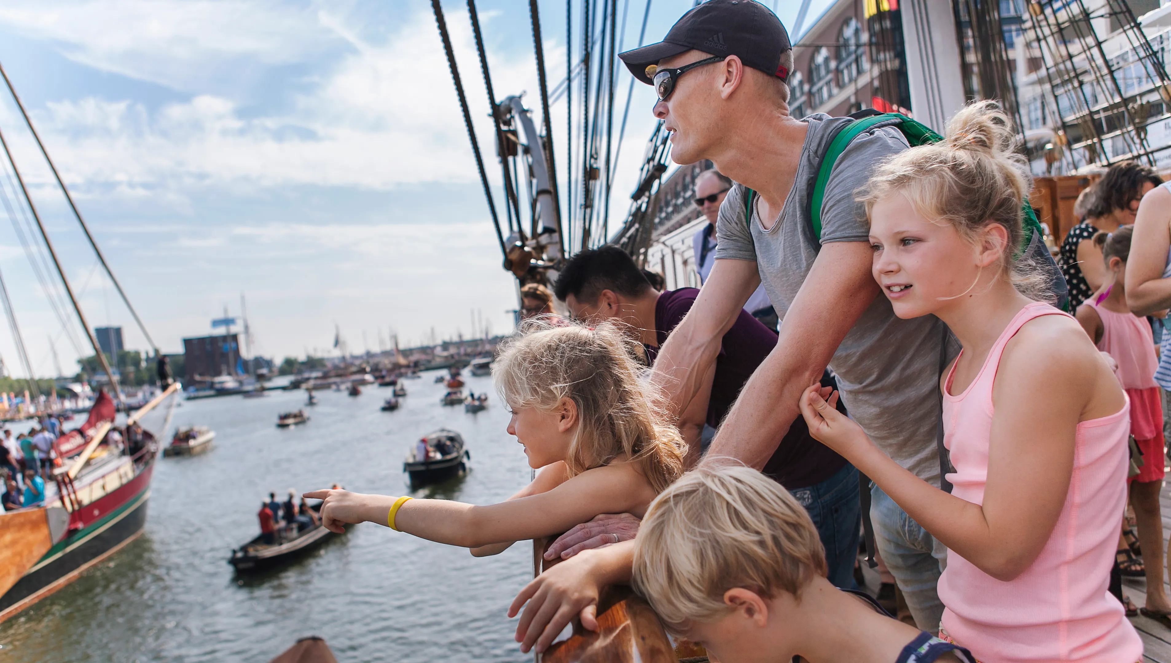 Bezoekers op de Christian Radich kijken naar de voorbijgaande bootjes.