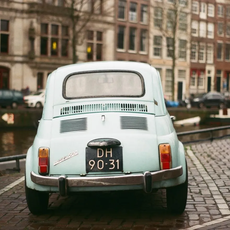 Blue vintage Fiat car parked by the canal.