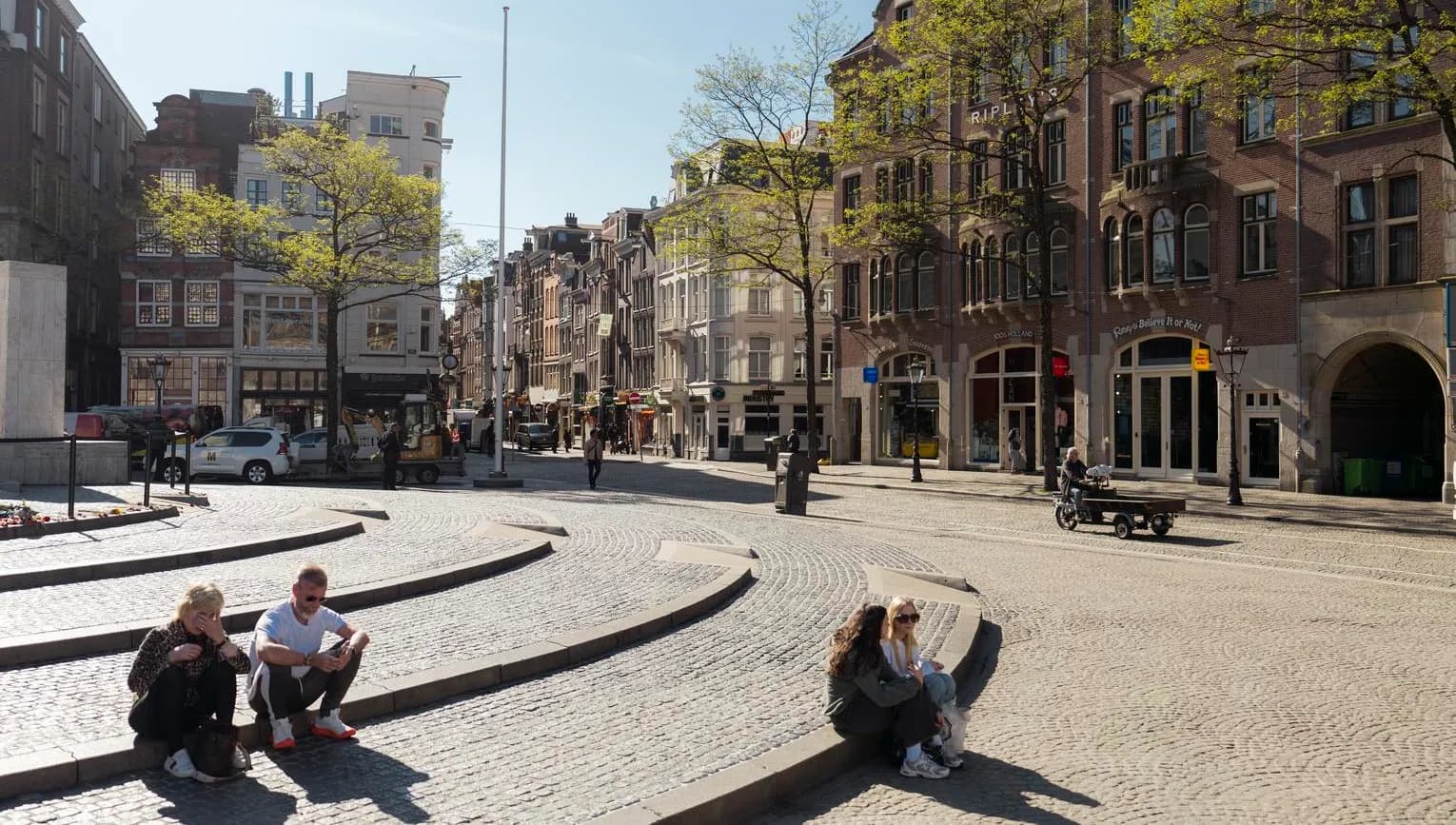 People enjoy the sun on Dam Square.