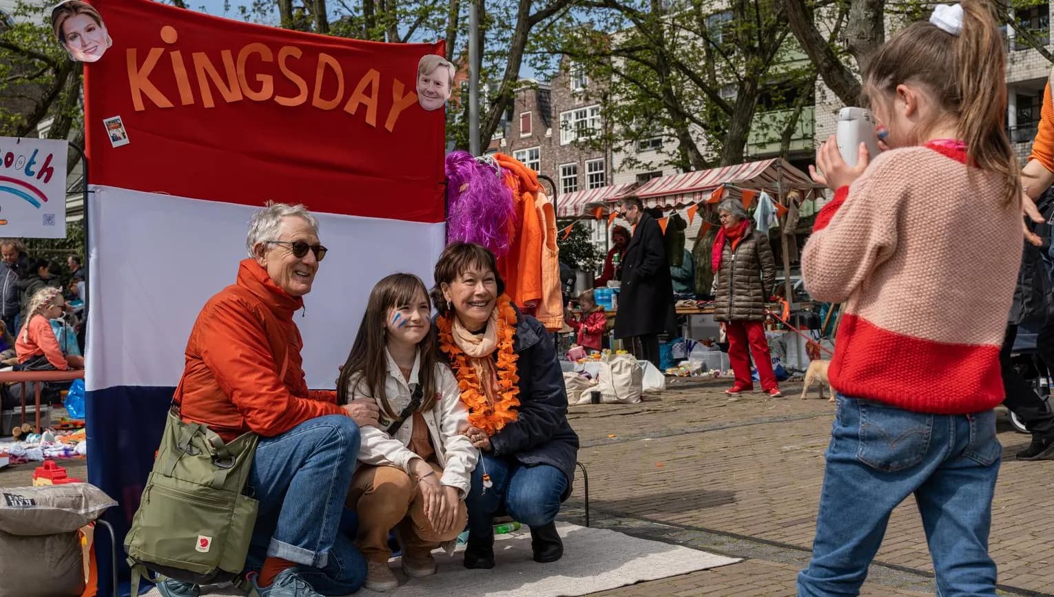 A family posing for a picture on the Amstelveld flea market on King's Day 2023.
