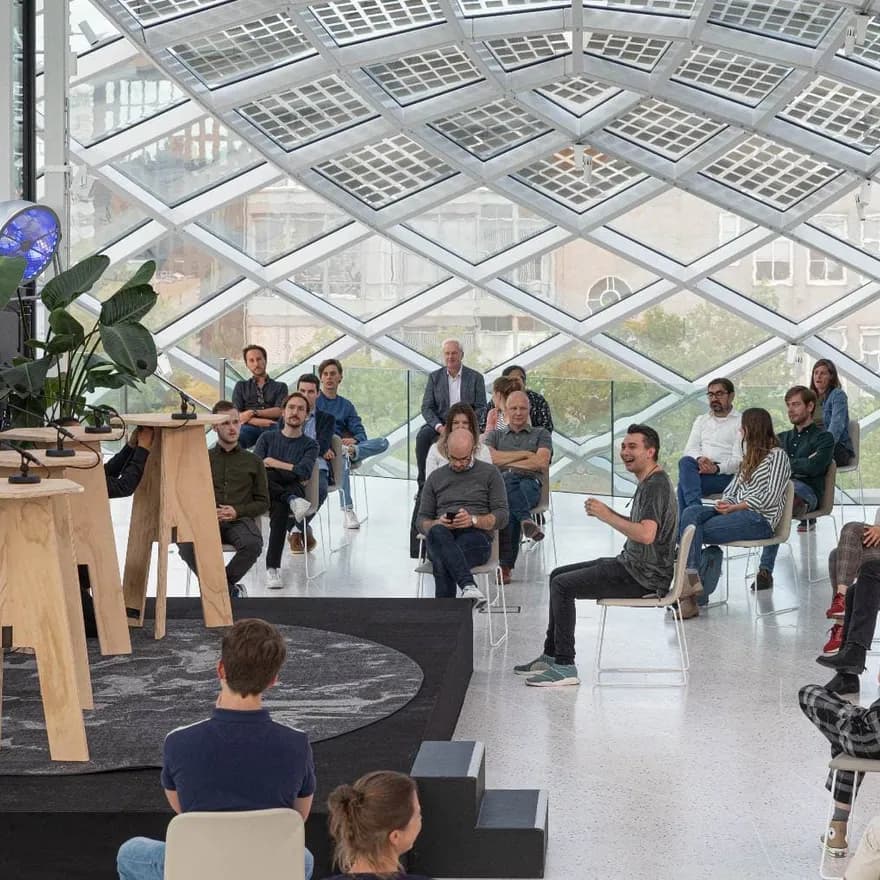 A hybrid event taking place at Capital C hotel in Amsterdam, with a stage and socially distanced audience members.