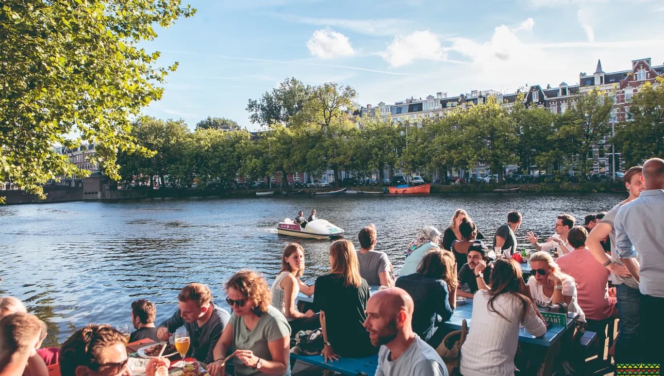 Waterkant people sitting on the terrace next to the water and a water bike passing by