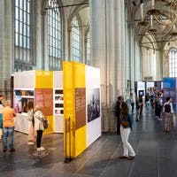 Visitors looking at photos in exhibition at World Press Photo 2023 in De Nieuwe Kerk