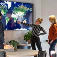 Polarsteps employees in their office pointing at a screen showing a world map.