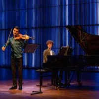 A violinist and a pianist on stage in het Muziekgebouw aan 't IJ