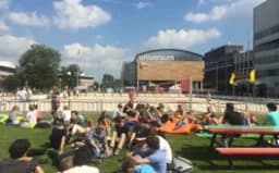 Students sitting on the grass in summer in front of University building of Physics UvA