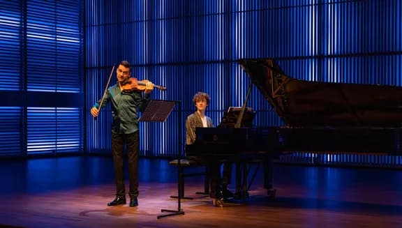 A violinist and a pianist on stage in het Muziekgebouw aan 't IJ