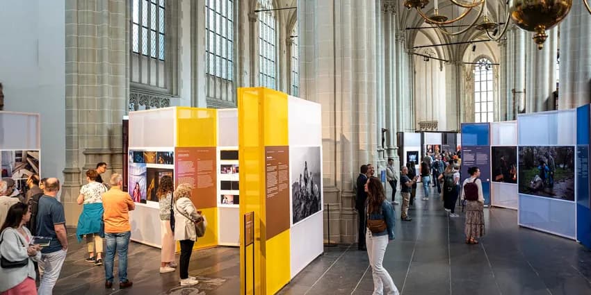 Visitors looking at photos in exhibition at World Press Photo 2023 in De Nieuwe Kerk