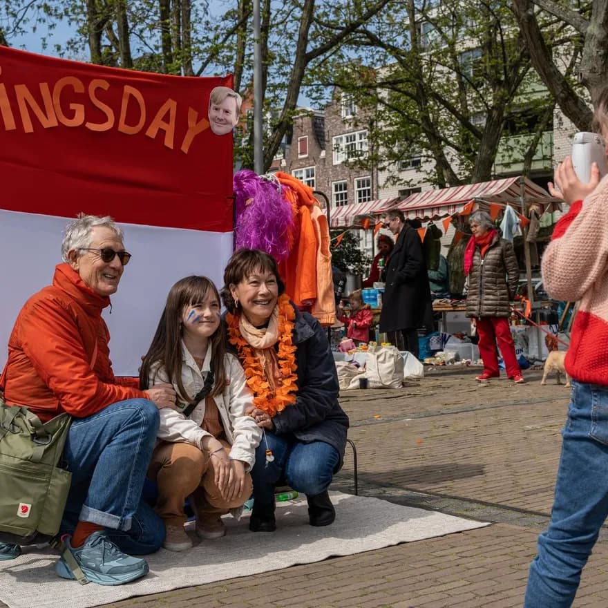 A family posing for a picture on the Amstelveld flea market on King's Day 2023.