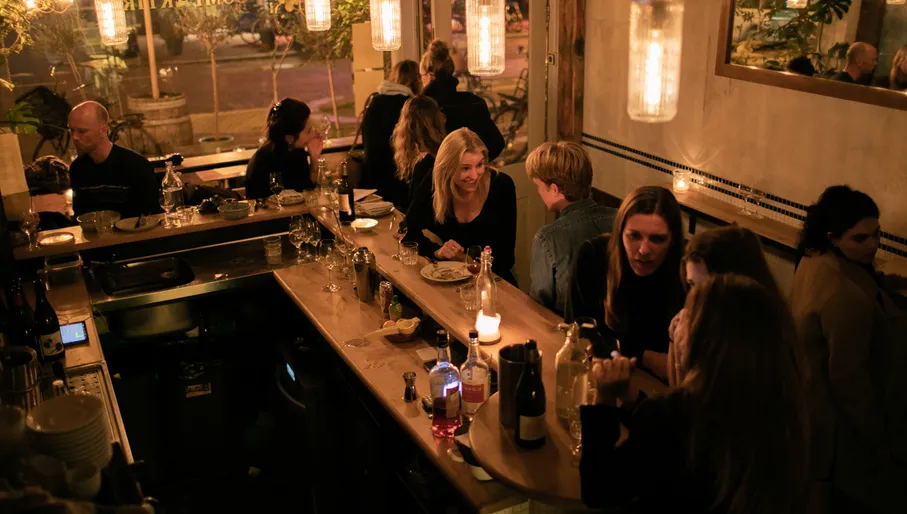 People sitting at bar at at Compartir wine bar and restaurant on Spaarndammerstraat