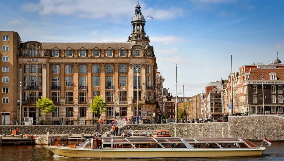 Art'otel Amsterdam exterior by day with a canal tour boat passing by in front