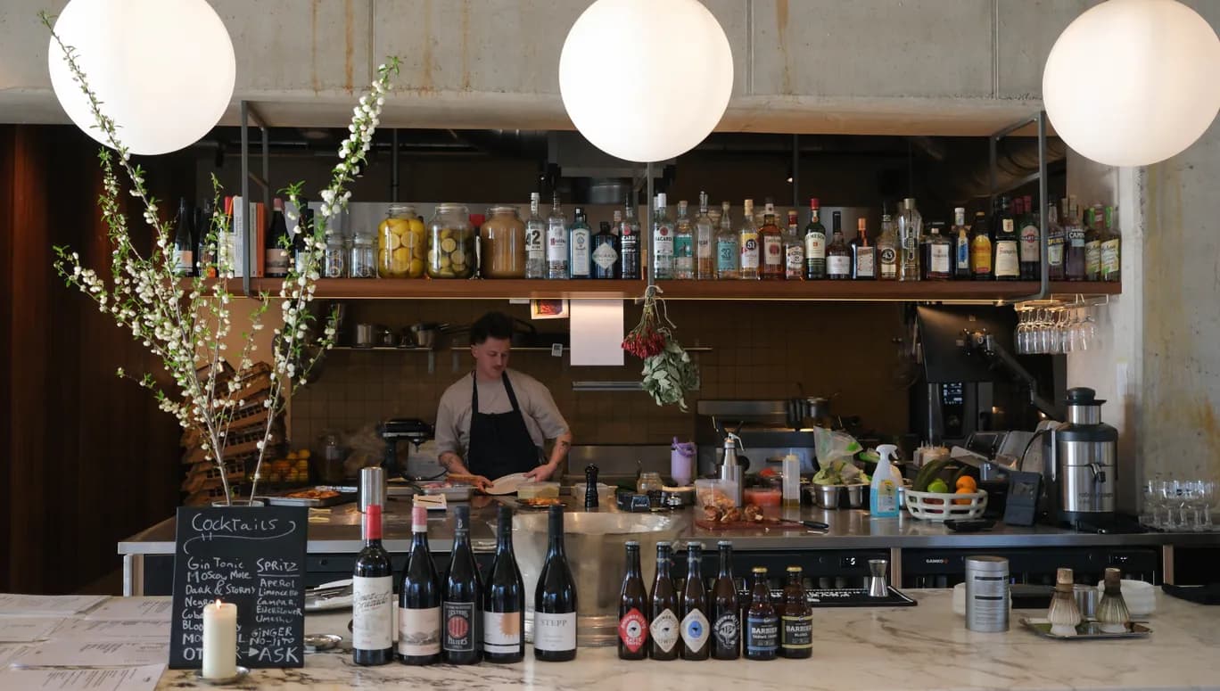 Interior of a cafe/restaurant Écluse, facing the bar where a cook is preparing food