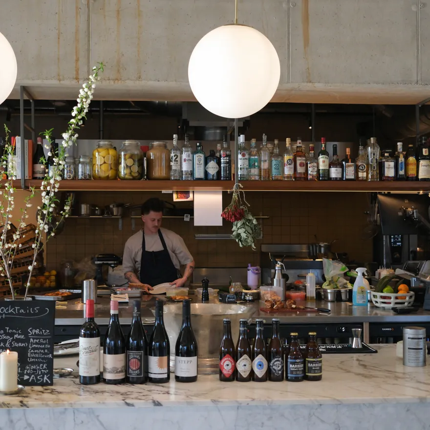 Interior of a cafe/restaurant Écluse, facing the bar where a cook is preparing food