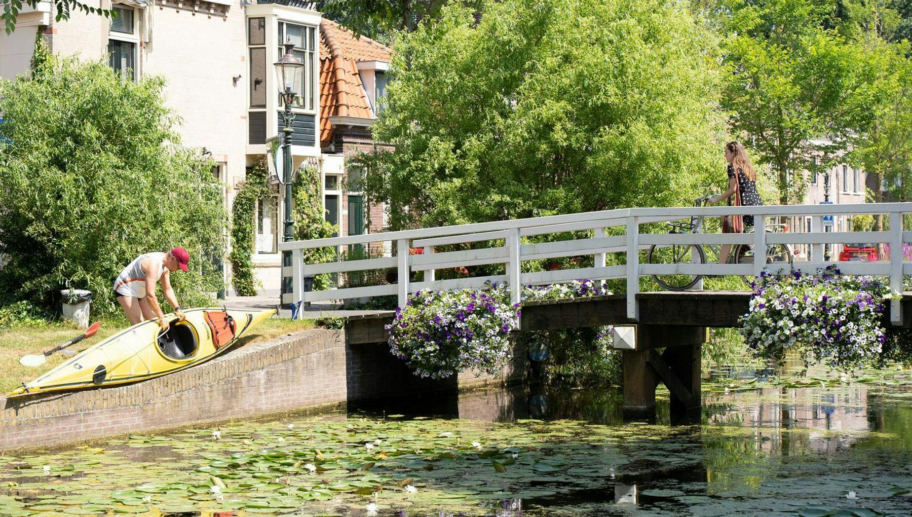 A man puts his canoe in the water at canal Weesp