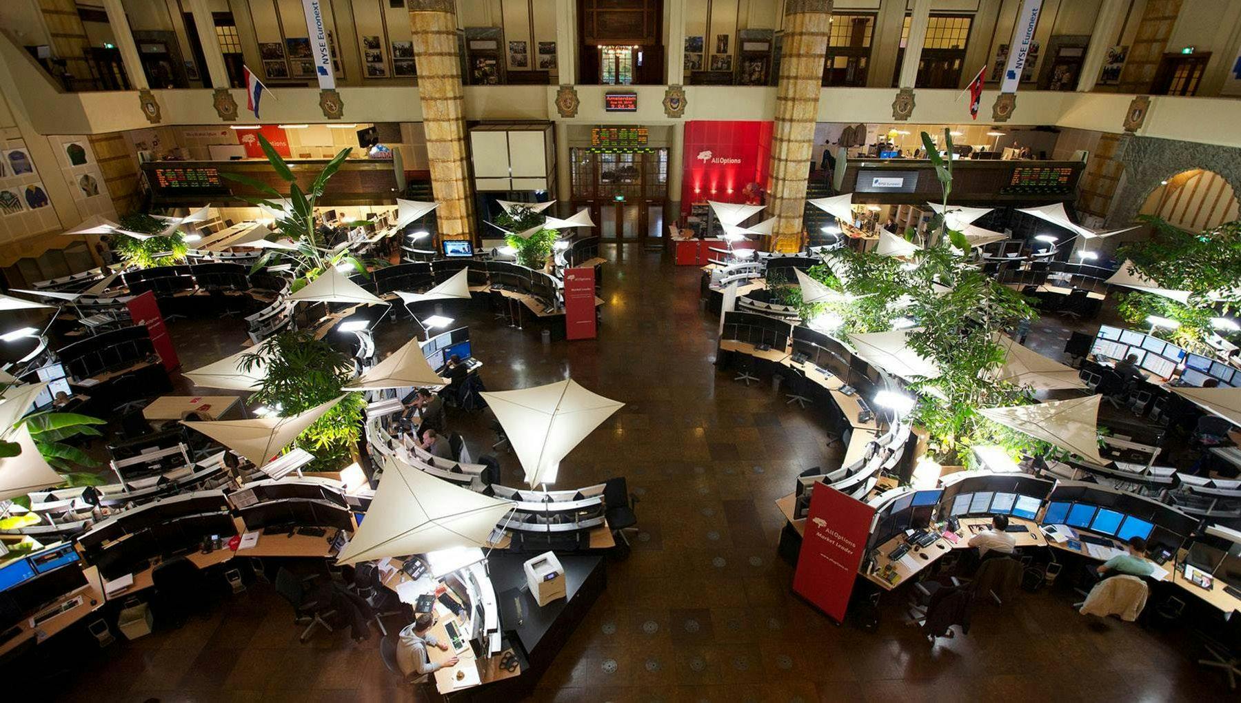 Bird's-eye view of a large stock exchange floor with multiple desks and computers.