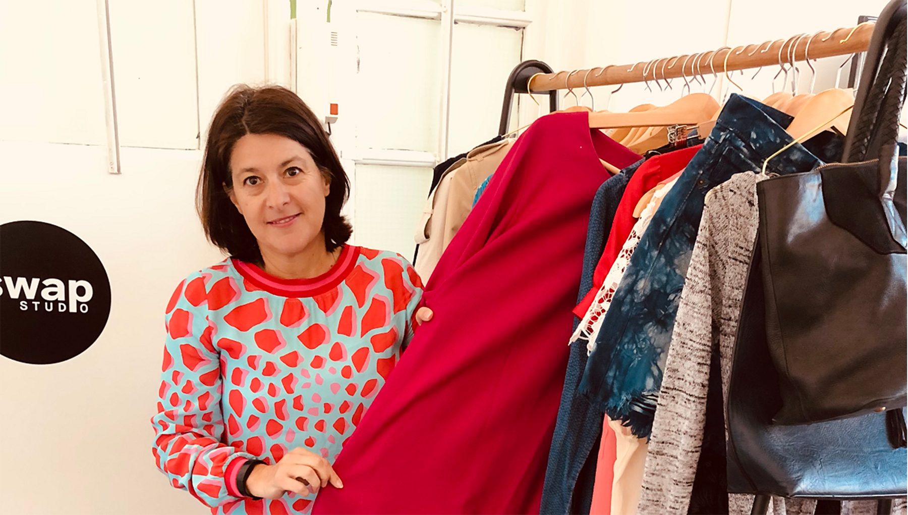 Kathryn Saducas, co-founder of Swap-Studio, shown in her office holding a dress on a clothing rail.