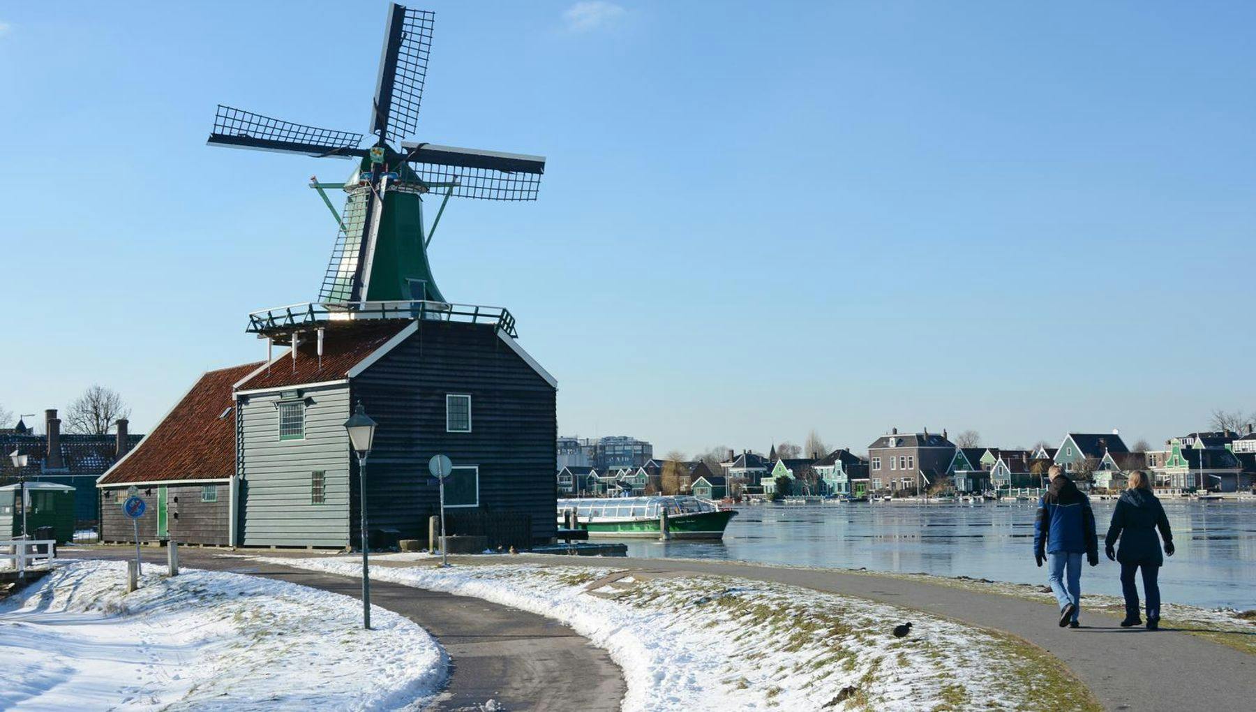 A couple is walking on a sunny day in the winter at the Zaanse Schans.