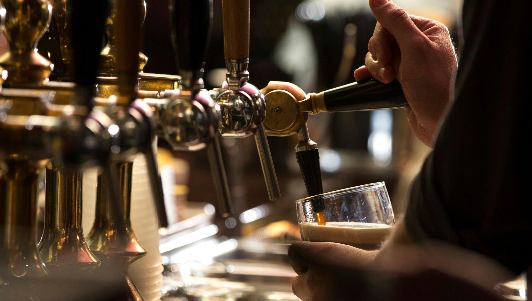 Closeup of a bartender pouring a dark stout beer in tap with subject and focus on the right