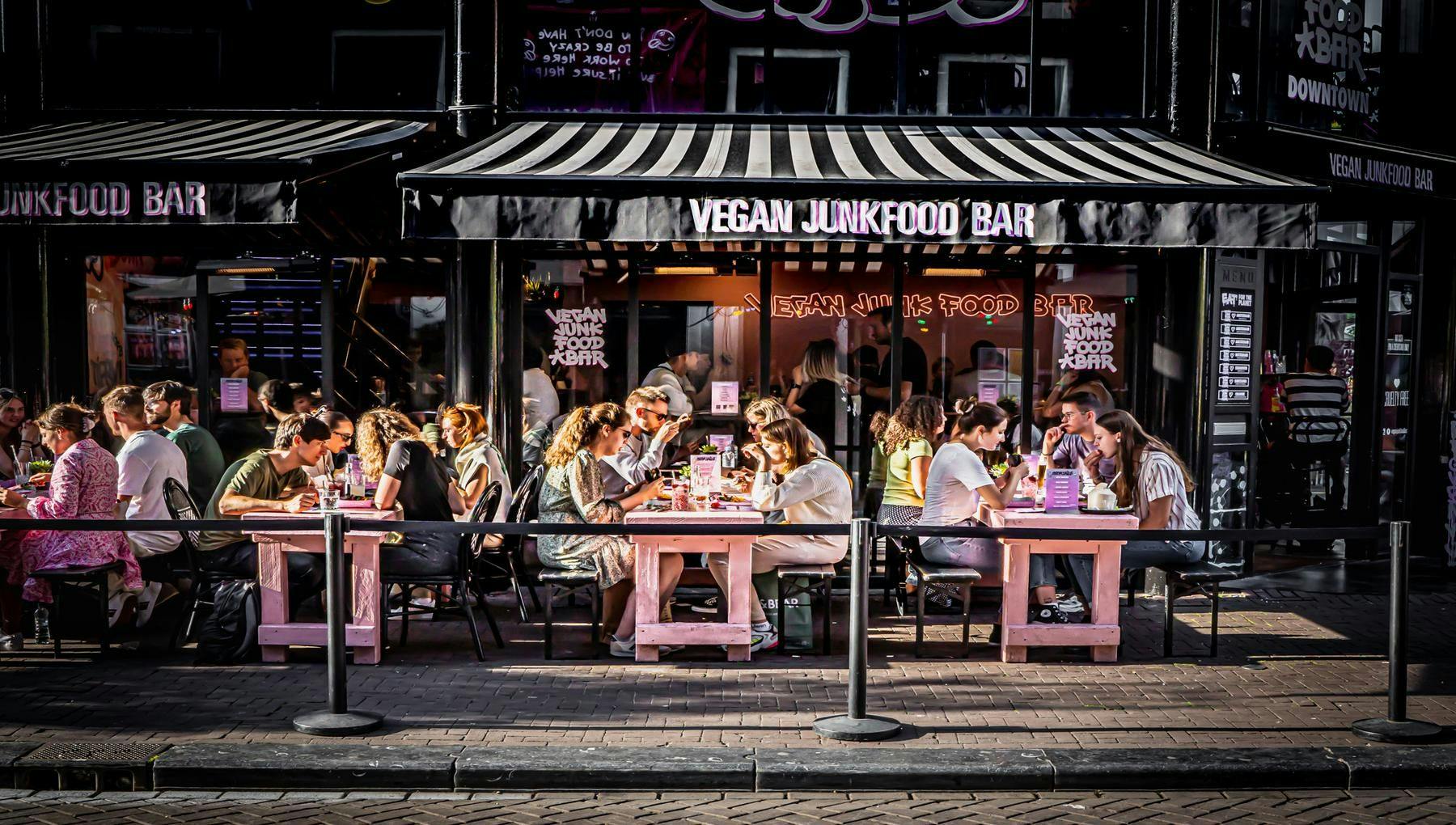 People sitting on terrace eating burgers at Vegan Junk Food bar