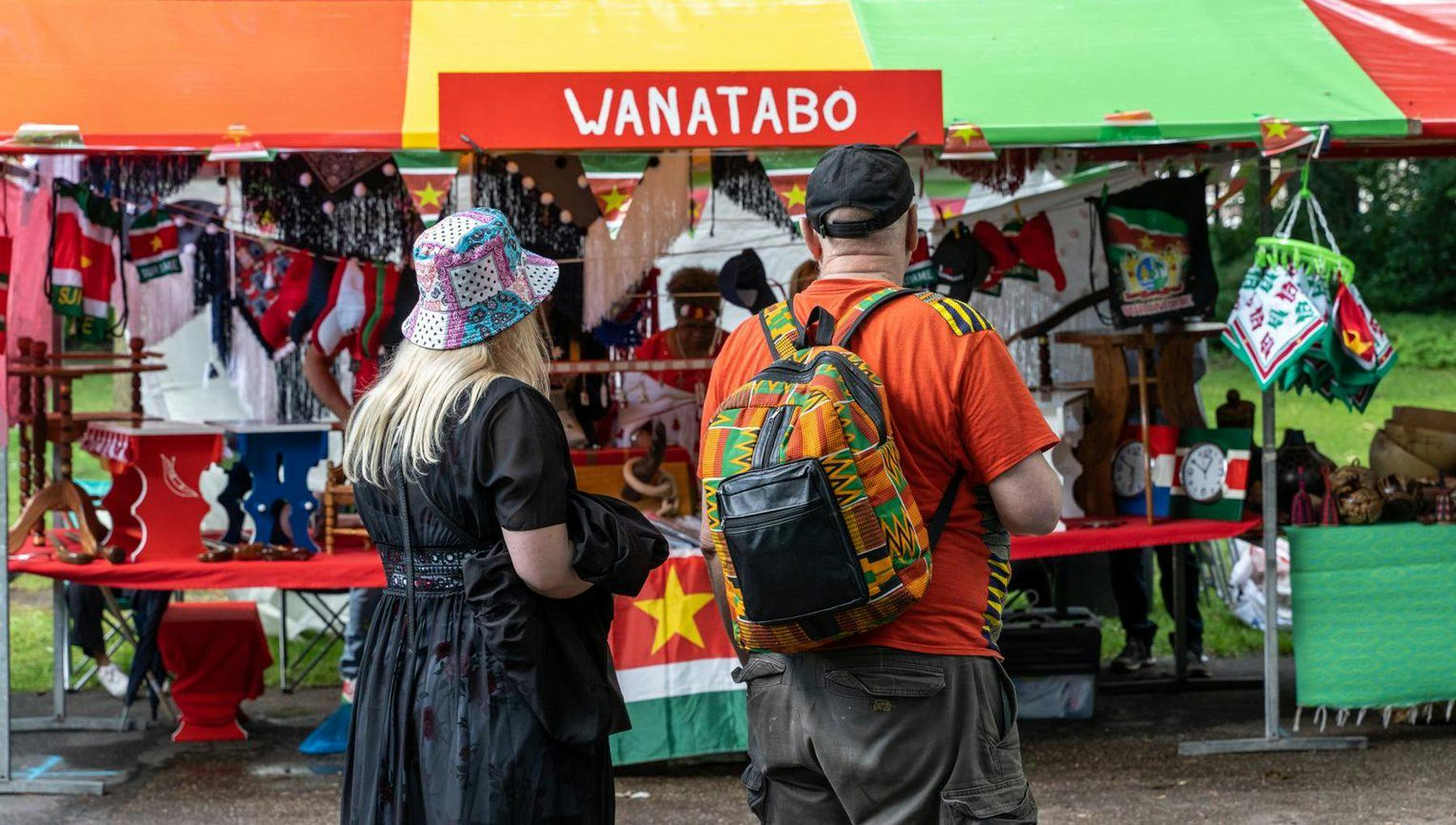 A couple standing in front of a stand during Keti Koti Festival 2022 in the Oosterpark.
