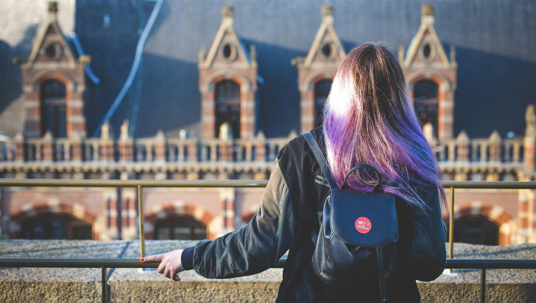 Woman standing on a rooftop with Startup sticker on bag.