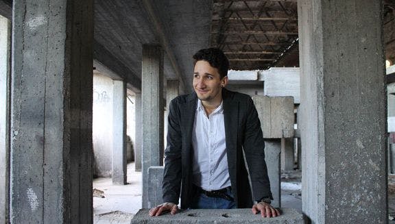 Portrait of Alvise Sembenico, Intrical co-founder, standing by raw concrete pillars.