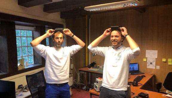 Floepp co-founders Jurriaan Vollebregt and Peter Bontenbal wearing Floepp sweaters holding Floepp sensors over their heads.