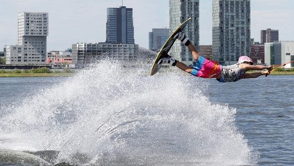 Wakeboarder doing jump at Cablepark Almere with city skyline