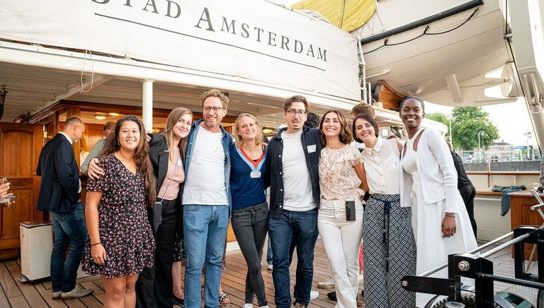 Photograph of StartupAmsterdam team having summer drinks, with "Stad Amsterdam" sign in background.