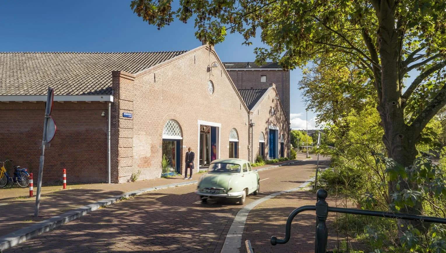 A oldtimer car driving over a sunny Entrepotdok during early autumn.