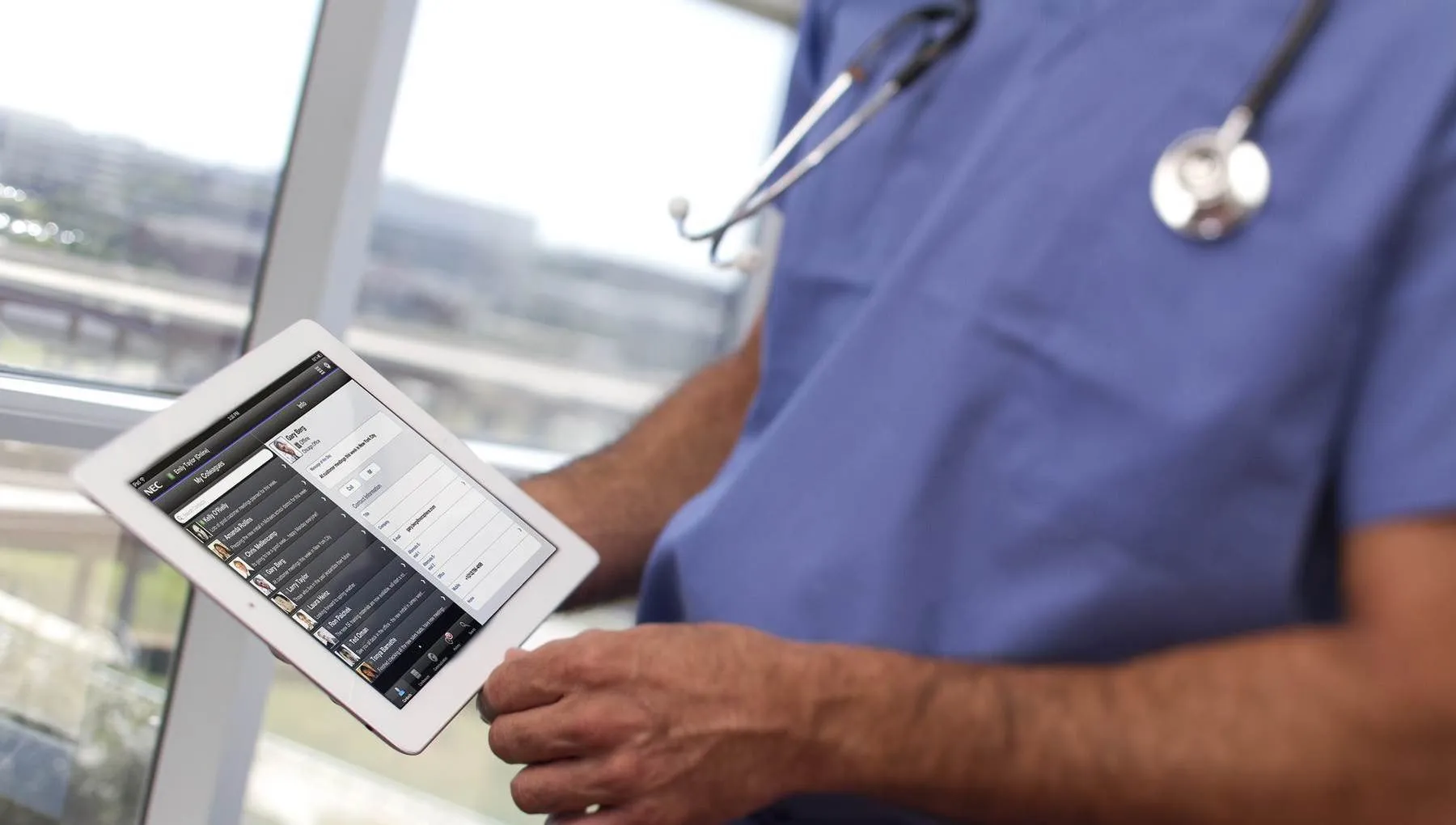 Close-up of a doctor's hands swiping through a tablet.