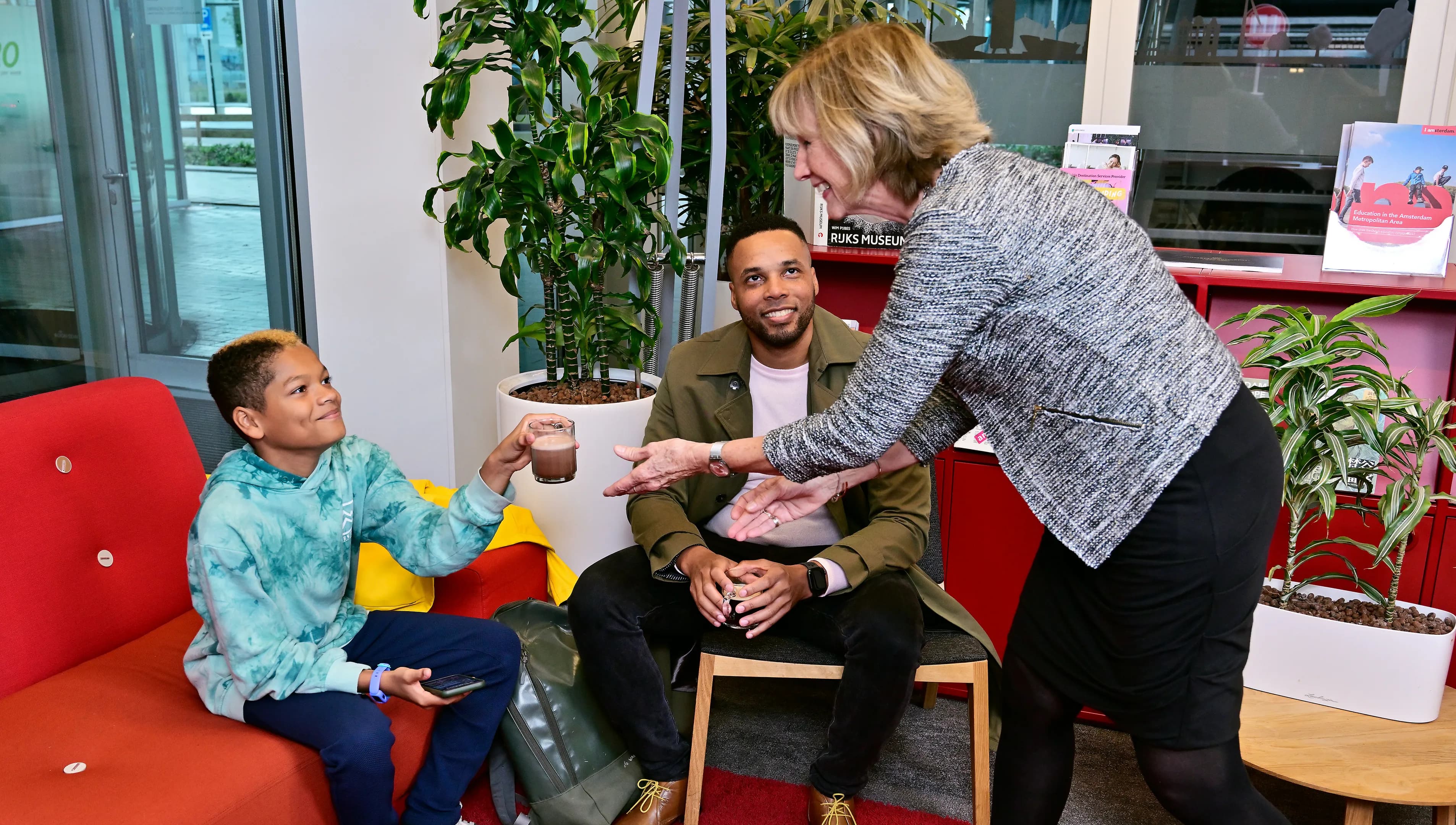 Father and son in the waiting room of the INAmsterdam offices, son gets a drink from INAmsterdam employee