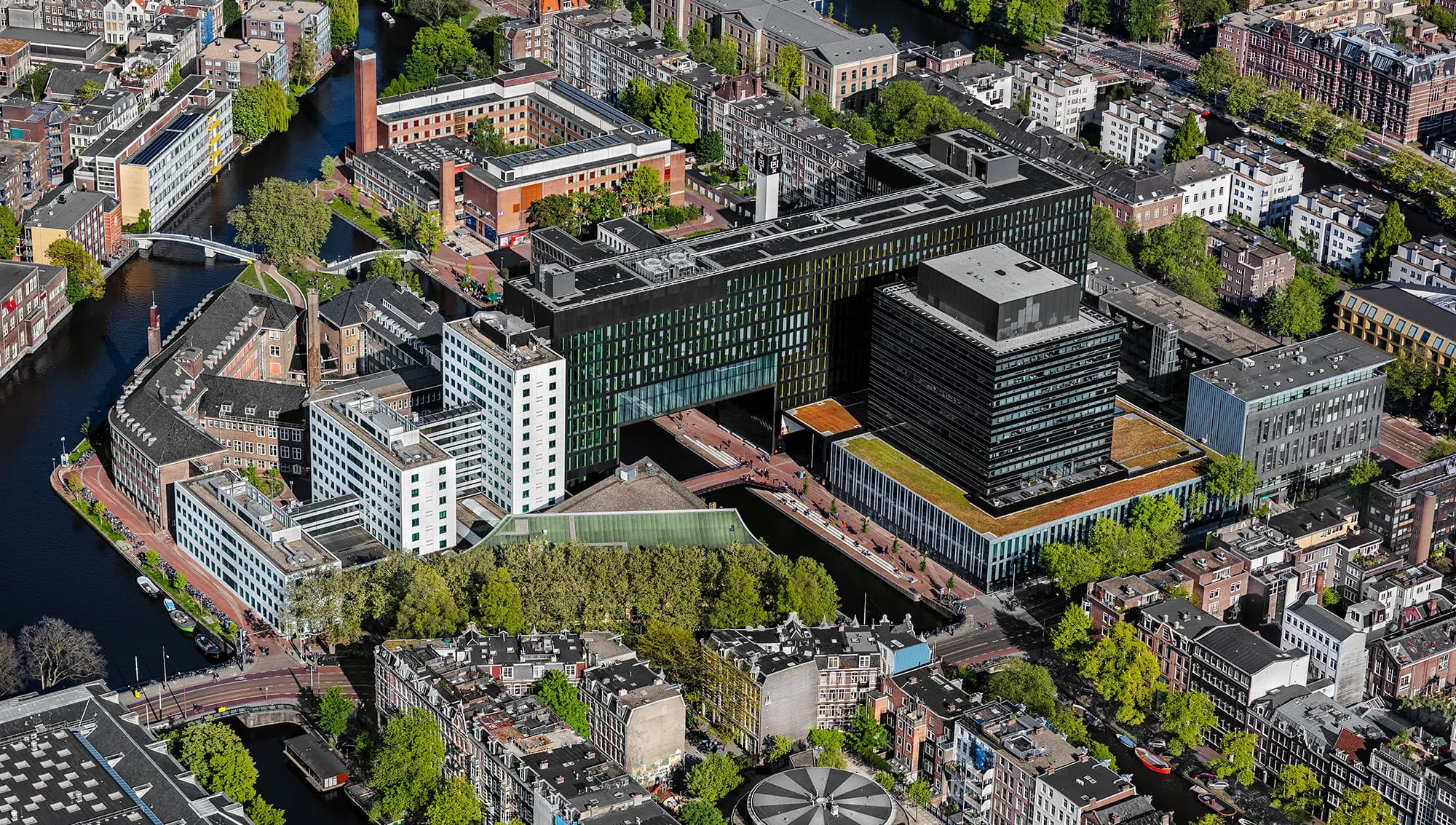 De Roeterseilandcampus is een van de vier open stadscampussen van de Universiteit van Amsterdam (UvA) en ligt in het centrum van Amsterdam. De campus is de thuisbasis voor de faculteiten Economie en Bedrijfskunde, Maatschappij en Gedragswetenschappen en sinds 2017 ook de faculteit der Rechtsgeleerdheid. Gebouw A: de Faculteit der Rechten, is ontworpen door Allford Hall Monaghan Morris. De bestaande gebouwen rondom de Nieuwe Achtergracht en de Plantage Muidergracht zijn de afgelopen jaren verbouwd zodat zij voldoen aan de hedendaagse eisen en behoeften van wetenschappelijk onderzoek en onderwijs. Ook de buitenruimte is opnieuw ingericht. Foto John Gundlach.