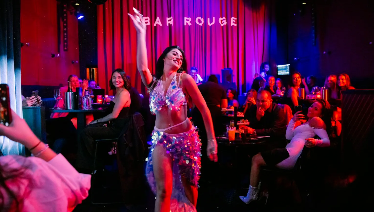Bar Rouge, interior with drinks and people in the bar, woman giving a show dancing and people smiling