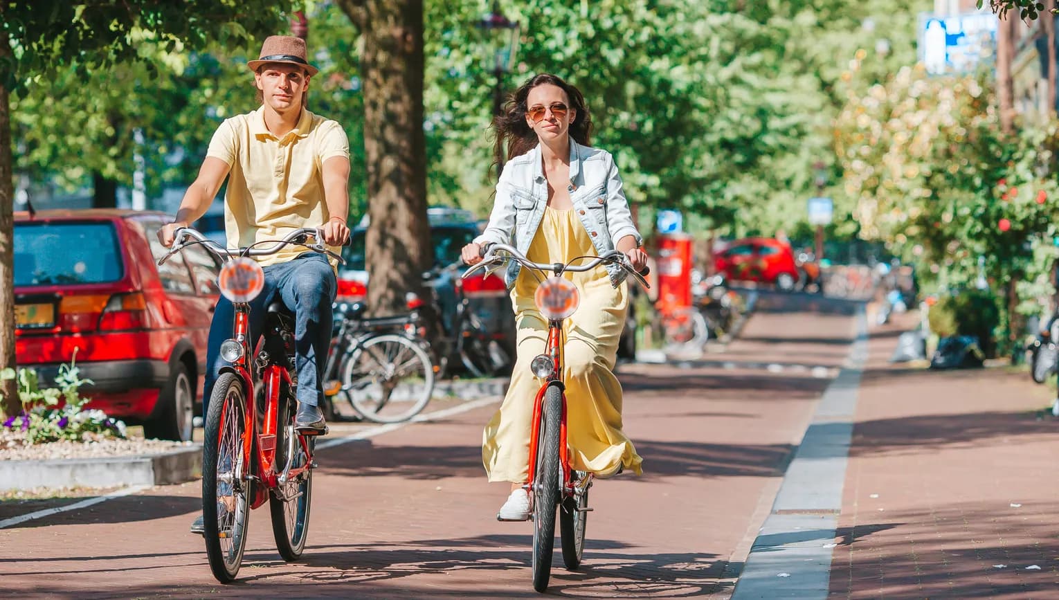 Young happy couple on red bikes cycling on the old streets in the city centre.