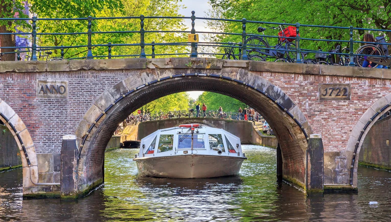 Canal cruise boat goes under the bridge over the Herengracht canal.