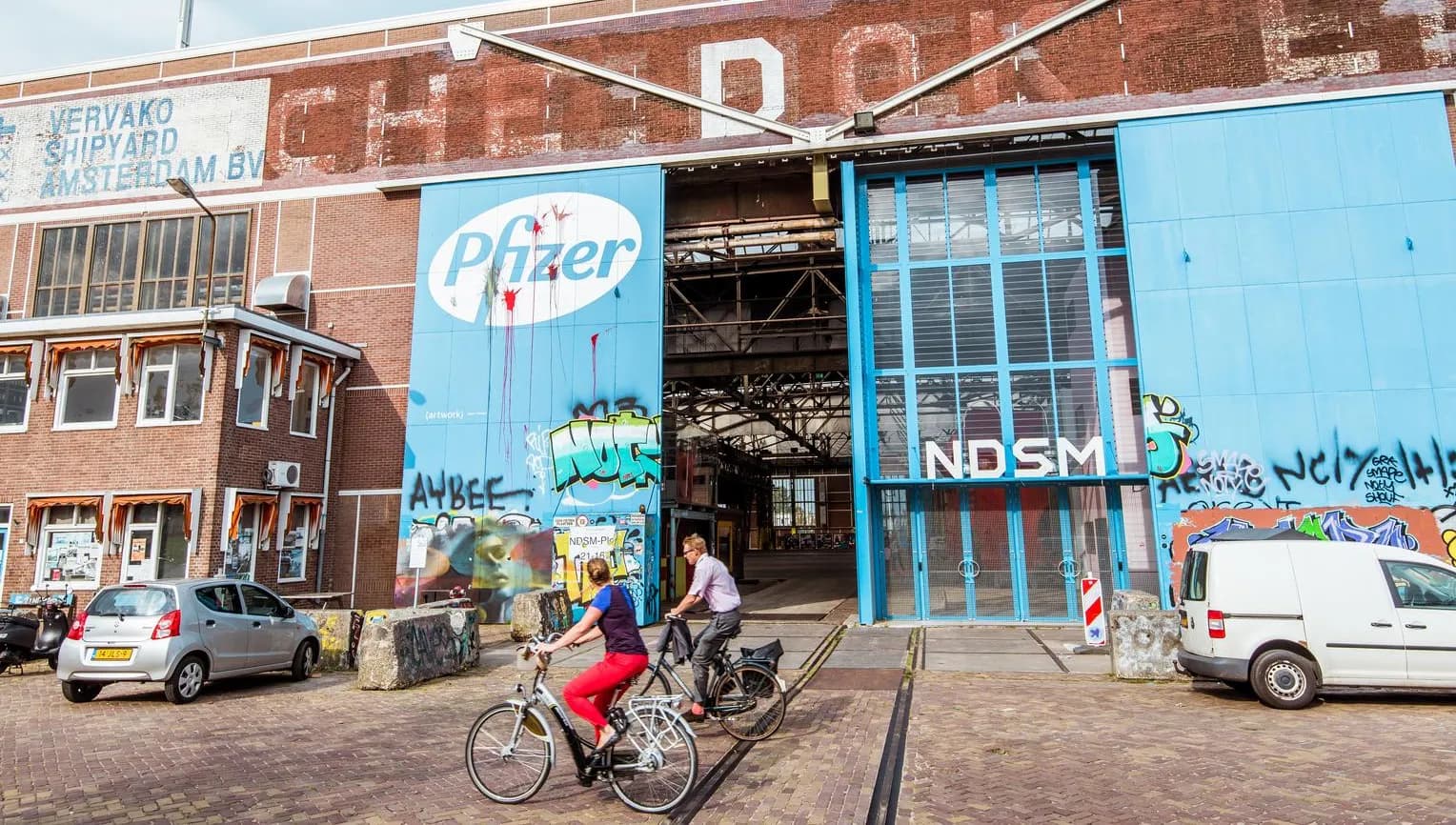 People cycling past IJhallen Pfizer Doors