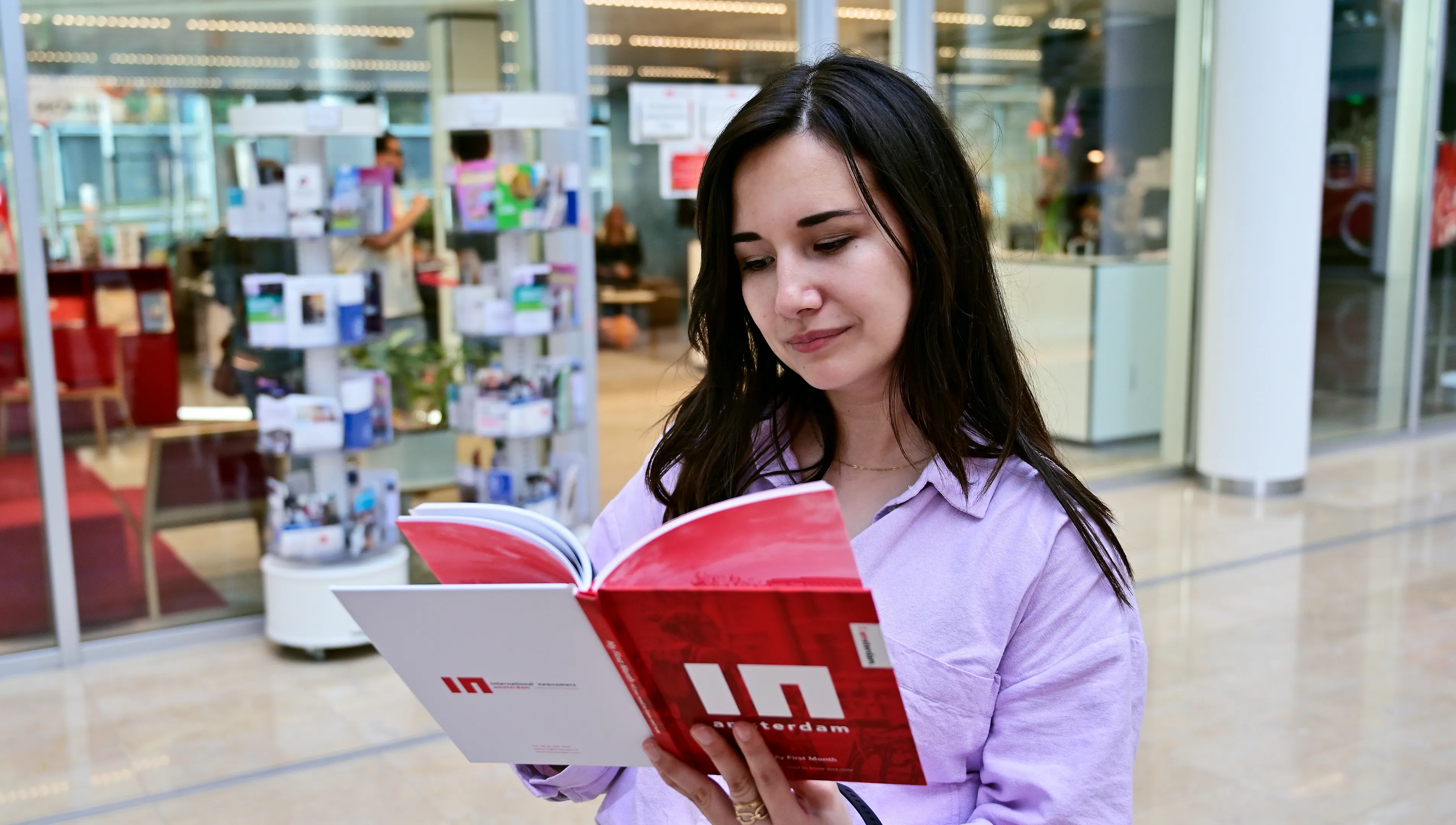 Woman reading INAmsterdam booklet in front of INAmsterdam offices
