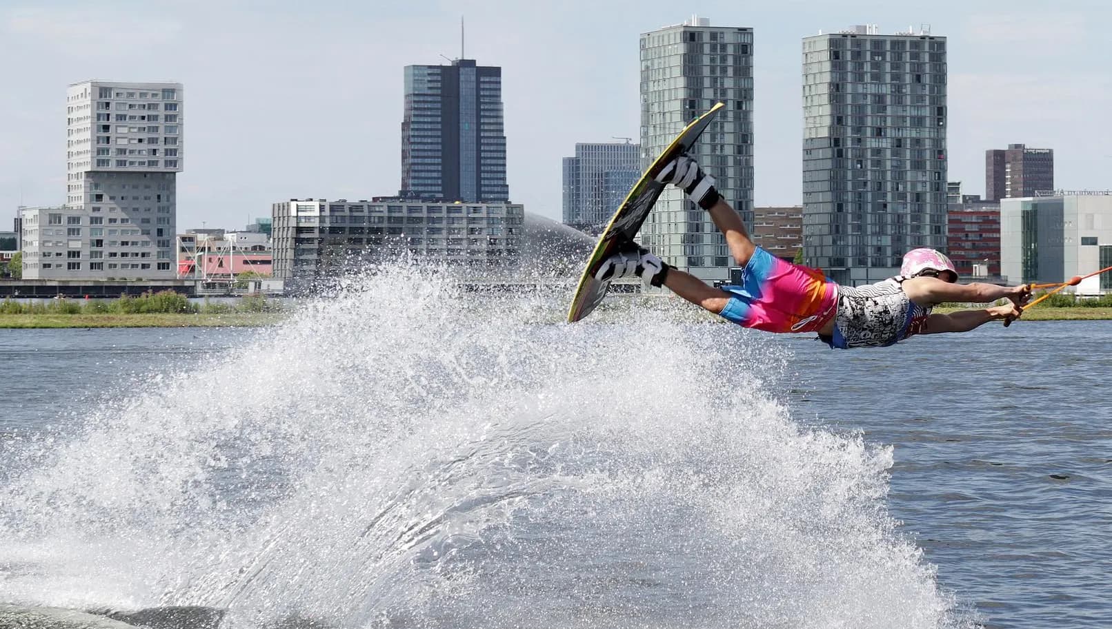 Wakeboarder doing jump at Cablepark Almere with city skyline