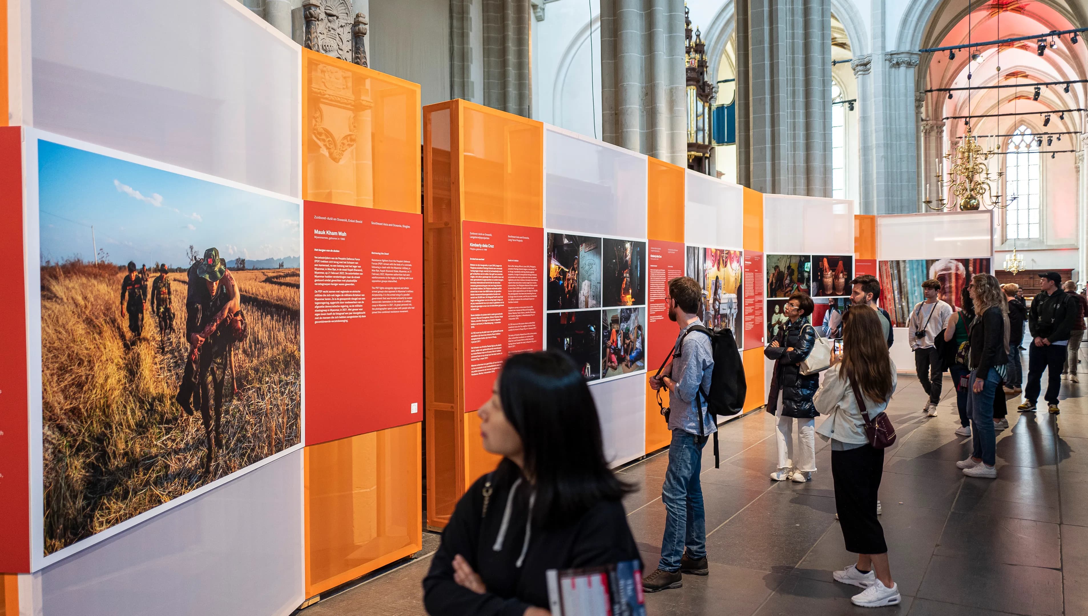 Visitors looking at photos in exhibition at World Press Photo 2023 in De Nieuwe Kerk